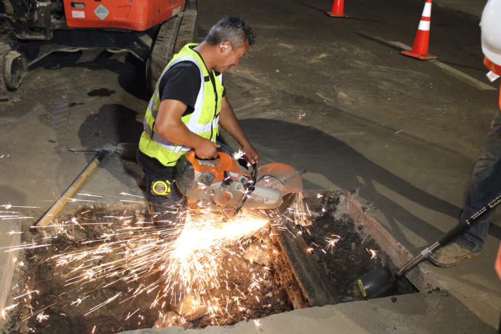 Trinity pipe layer cutting pipe with a cut-off saw during a night tie-in