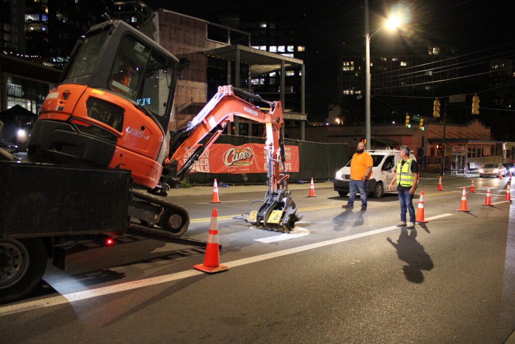 Trinity crew and mini excavator on a night water-line tie-in on Broadway in Nashville